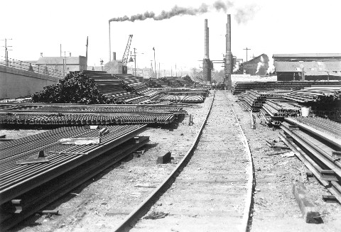 Rail unloading & storage yard; rolling mill in the background.